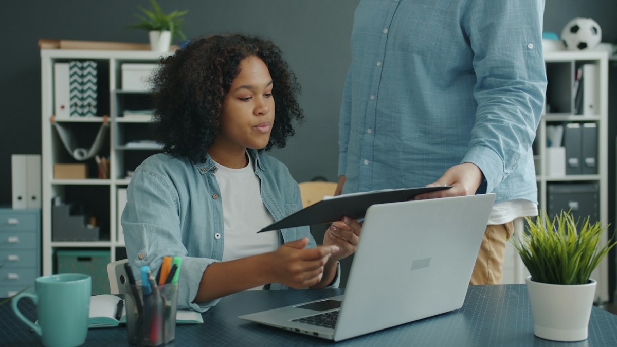 Two colleagues going over a document beside a laptop